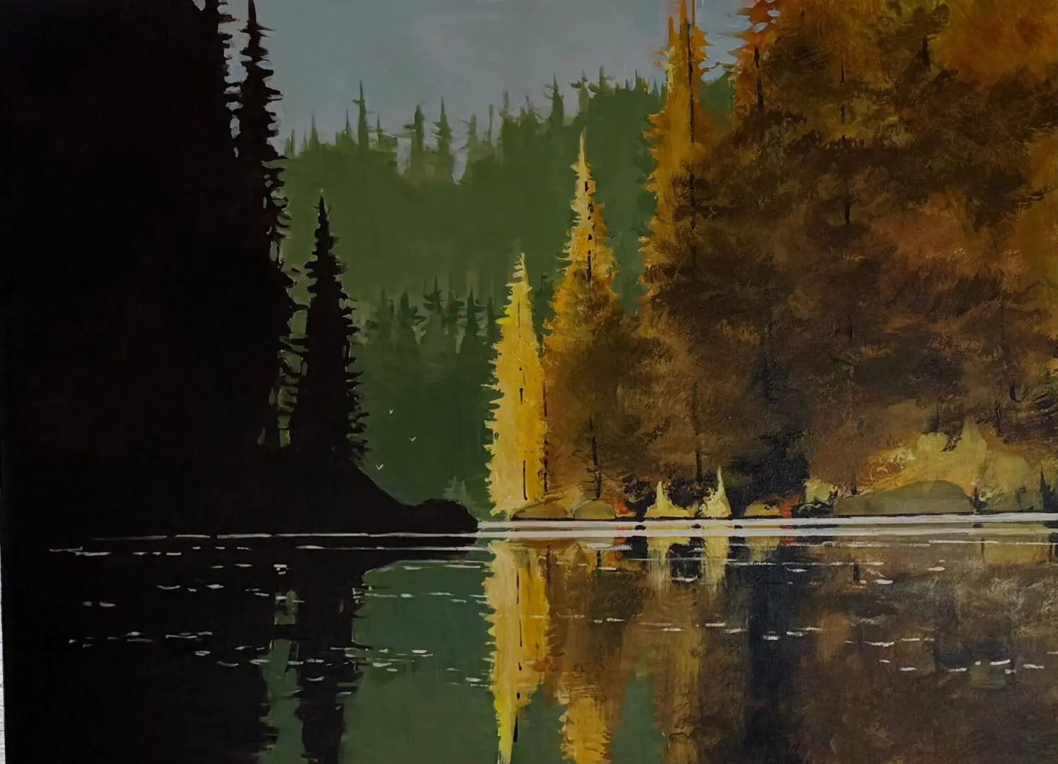 Forest landscape reflecting on a calm lake.